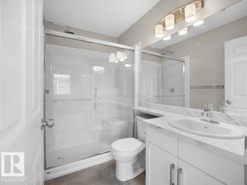 Bathroom with vanity, a shower stall, and dark tile patterned flooring - 15 7385 Edgemont Way, Edmonton, AB - Indoor Photo Showing Bathroom
