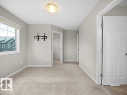 Unfurnished bedroom featuring a walk in closet, light colored carpet, and a textured ceiling - 