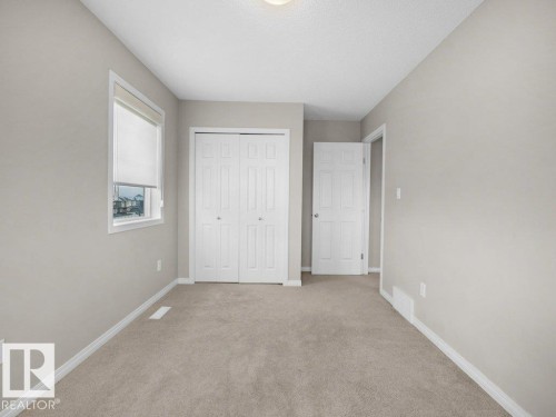 Unfurnished bedroom featuring light colored carpet, a closet, and a textured ceiling - 15 7385 Edgemont Way, Edmonton, AB - Indoor Photo Showing Other Room