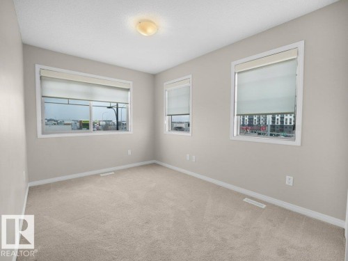 Spare room featuring light carpet and baseboards - 15 7385 Edgemont Way, Edmonton, AB - Indoor Photo Showing Other Room