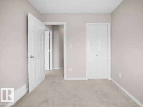 Unfurnished bedroom with light carpet, a textured ceiling, and a closet - 15 7385 Edgemont Way, Edmonton, AB - Indoor Photo Showing Other Room