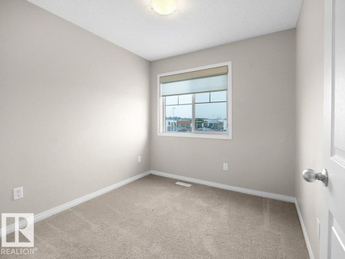 Unfurnished room with light carpet and a textured ceiling - 15 7385 Edgemont Way, Edmonton, AB - Indoor Photo Showing Other Room