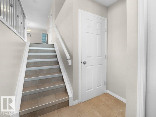 Stairs featuring tile patterned floors and baseboards - 15 7385 Edgemont Way, Edmonton, AB - Indoor Photo Showing Other Room
