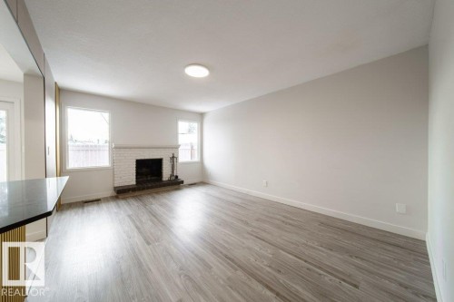Unfurnished living room with light wood finished floors and a fireplace - 13833 24 Street, Edmonton, AB - Indoor Photo Showing Living Room With Fireplace