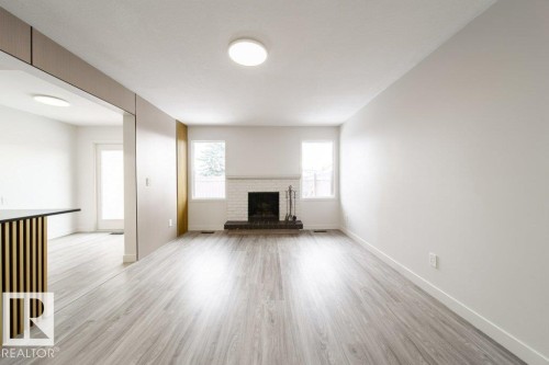Unfurnished living room featuring light wood-style floors and a fireplace - 13833 24 Street, Edmonton, AB - Indoor Photo Showing Living Room With Fireplace