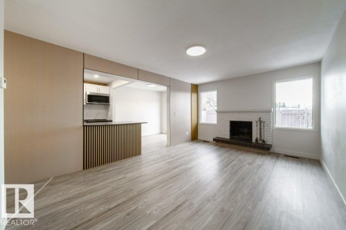 Unfurnished living room with light wood finished floors and a brick fireplace - 13833 24 Street, Edmonton, AB - Indoor Photo Showing Living Room With Fireplace