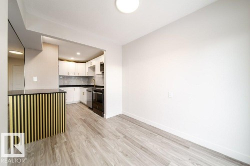 Kitchen featuring white cabinetry, dark countertops, light wood-type flooring, decorative backsplash, and black stove - 13833 24 Street, Edmonton, AB - Indoor
