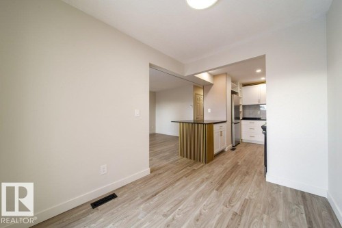 Kitchen with dark countertops, light wood-style flooring, white cabinets, freestanding refrigerator, and a kitchen island - 13833 24 Street, Edmonton, AB - Indoor