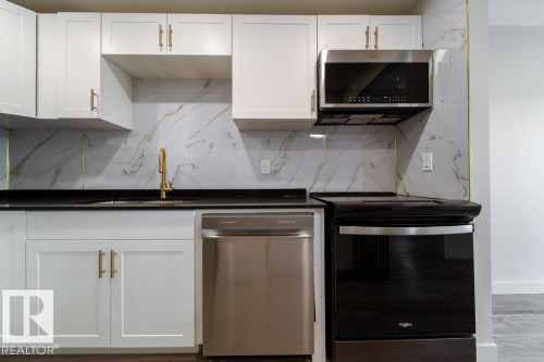 Kitchen with stainless steel appliances, white cabinets, backsplash, and wood finished floors - 13833 24 Street, Edmonton, AB - Indoor Photo Showing Kitchen