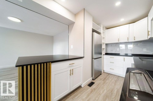 Kitchen featuring open shelves, light wood-type flooring, white cabinets, freestanding refrigerator, and decorative backsplash - 13833 24 Street, Edmonton, AB - Indoor Photo Showing Kitchen