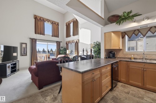 Kitchen with dark countertops, a peninsula, open floor plan, a high ceiling, and backsplash - 427 13005 140 Avenue, Edmonton, AB - Indoor Photo Showing Kitchen