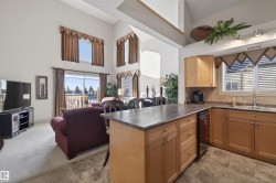 Kitchen with dark countertops, a peninsula, open floor plan, a high ceiling, and backsplash - 