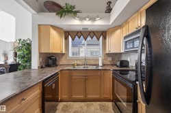 Kitchen featuring black appliances, tasteful backsplash, and light stone finish flooring - 