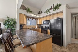 Kitchen with black appliances, a peninsula, dark countertops, tasteful backsplash, and a breakfast bar area - 