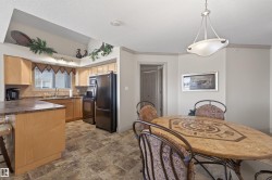 Kitchen featuring black appliances, dark countertops, pendant lighting, ornamental molding, and stone finish flooring - 