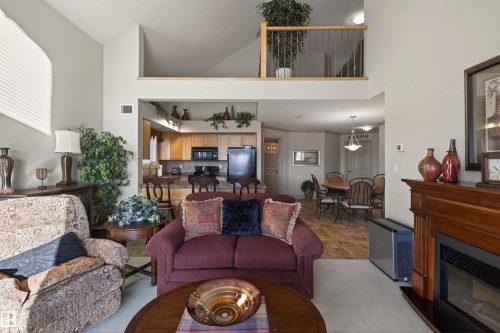 Living room featuring a glass covered fireplace and a high ceiling - 427 13005 140 Avenue, Edmonton, AB - Indoor Photo Showing Living Room With Fireplace