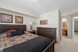 Bedroom featuring a closet, a textured ceiling, light carpet, and connected bathroom - 