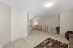 Living area featuring an upstairs landing, a textured ceiling, and light colored carpet - 