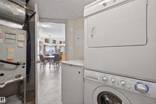 Laundry area featuring electric panel, stacked washer and dryer, and heating unit - 427 13005 140 Avenue, Edmonton, AB - Indoor Photo Showing Laundry Room