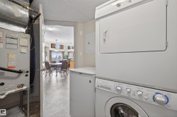 Laundry area featuring electric panel, stacked washer and dryer, and heating unit - 