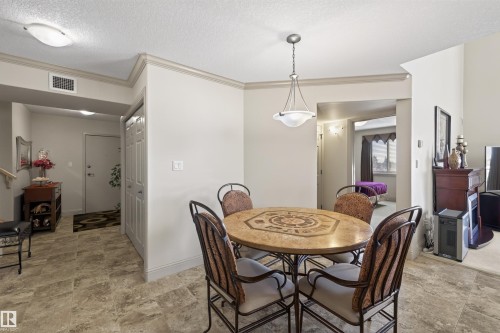 Dining area with a textured ceiling, stone finish flooring, and ornamental molding - 427 13005 140 Avenue, Edmonton, AB - Indoor Photo Showing Dining Room