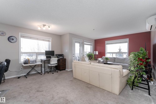 Carpeted living room featuring an office area and a textured ceiling - 325 1520 Hammond Gate, Edmonton, AB - Indoor