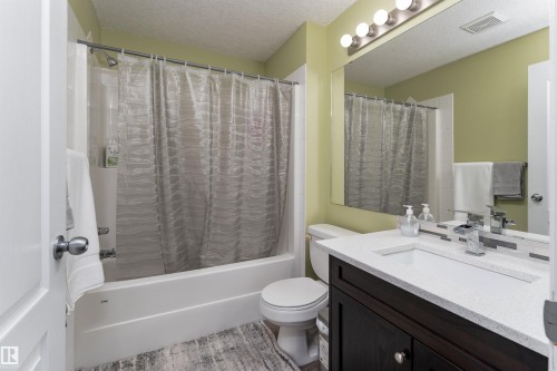 Full bathroom featuring a textured ceiling, vanity, and shower / bath combo - 325 1520 Hammond Gate, Edmonton, AB - Indoor Photo Showing Bathroom