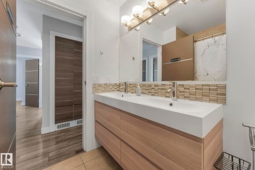 Full bathroom with double vanity, backsplash, curtained shower, and light tile patterned floors - 14924 81 Street, Edmonton, AB 