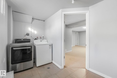 Laundry room featuring washing machine and dryer, light tile patterned flooring, and light carpet - 14924 81 Street, Edmonton, AB 