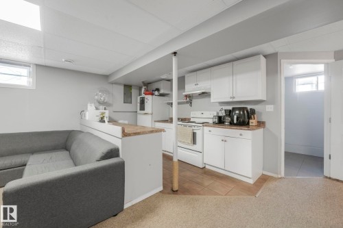 Kitchen featuring healthy amount of natural light, white cabinets, white appliances, light tile patterned floors, and a drop ceiling - 14924 81 Street, Edmonton, AB 