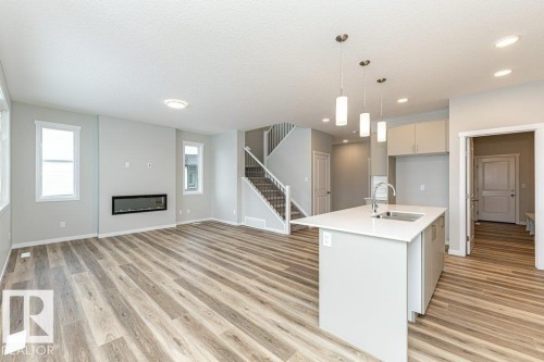 Kitchen featuring pendant lighting, open floor plan, an island with sink, light wood finished floors, and a textured ceiling - 3949 Wren Loop, Edmonton, AB - Indoor Photo Showing Kitchen