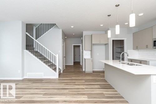 Kitchen featuring gray cabinetry, pendant lighting, backsplash, light wood-style floors, and a textured ceiling - 3949 Wren Loop, Edmonton, AB - Indoor Photo Showing Kitchen With Double Sink With Upgraded Kitchen