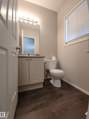 Half bathroom with vanity, dark wood-type flooring, and a textured ceiling - 5424 204 Street, Edmonton, AB - Indoor Photo Showing Bathroom