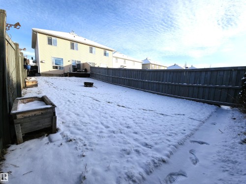 Yard layered in snow with a fenced backyard, a residential view, and a deck - 5424 204 Street, Edmonton, AB - Outdoor