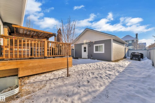 View of snowy exterior with a deck, board and batten siding, and an outbuilding - 7613 16 Av Sw, Edmonton, AB - Outdoor