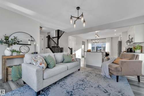 Living area with a chandelier and wood finished floors - 7613 16 Av Sw, Edmonton, AB - Indoor Photo Showing Living Room
