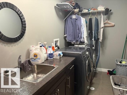 Laundry area featuring separate washer and dryer and sink and cabinet space - 867 Armitage Wynd Sw, Edmonton, AB - Indoor Photo Showing Laundry Room