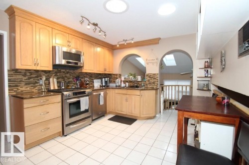 Kitchen with light wood finish cabinets, stainless steel appliances, light tile patterned floors, and tasteful backsplash - 2812 35 Street Nw, Edmonton, AB - Indoor Photo Showing Kitchen