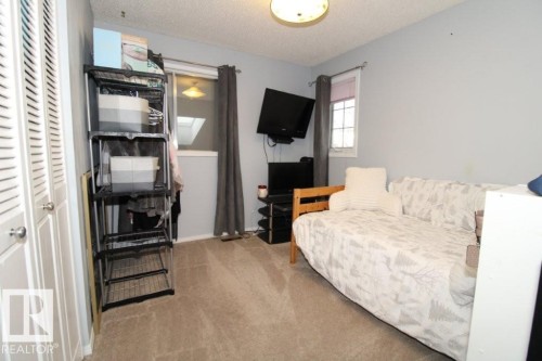 Bedroom featuring a textured ceiling, light colored carpet, and a closet - 2812 35 Street Nw, Edmonton, AB - Indoor