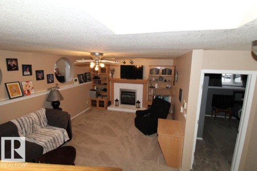 Carpeted living room with a glass covered fireplace, a textured ceiling, and ceiling fan - 2812 35 Street Nw, Edmonton, AB - Indoor With Fireplace