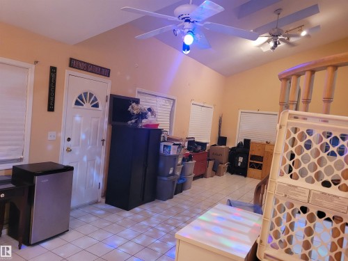 Interior space with ceiling fan, light tile patterned floors, stainless steel refrigerator, and vaulted ceiling - 2812 35 Street Nw, Edmonton, AB - Indoor Photo Showing Other Room