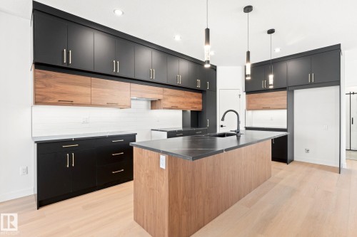 Kitchen with light wood-style flooring, a kitchen island with sink, hanging light fixtures, two tone color scheme, and modern cabinets - 94 Blackbird Bend, Fort Saskatchewan, AB - Indoor Photo Showing Kitchen With Upgraded Kitchen