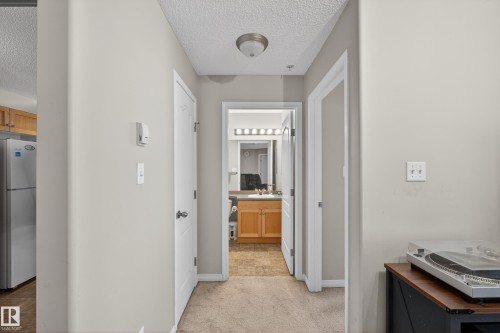 Corridor featuring a textured ceiling and light colored carpet - 131 1520 Hammong Gate, Edmonton, AB - Indoor Photo Showing Other Room