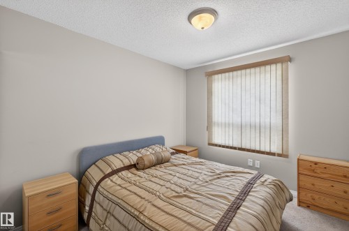 Carpeted bedroom with a textured ceiling - 131 1520 Hammong Gate, Edmonton, AB - Indoor Photo Showing Bedroom