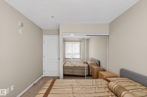 Bedroom with carpet flooring, a textured ceiling, and a closet - 131 1520 Hammong Gate, Edmonton, AB - Indoor Photo Showing Bedroom