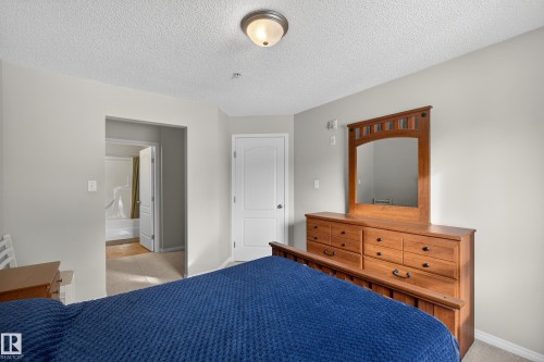 Bedroom with a textured ceiling and light carpet - 131 1520 Hammong Gate, Edmonton, AB - Indoor Photo Showing Bedroom