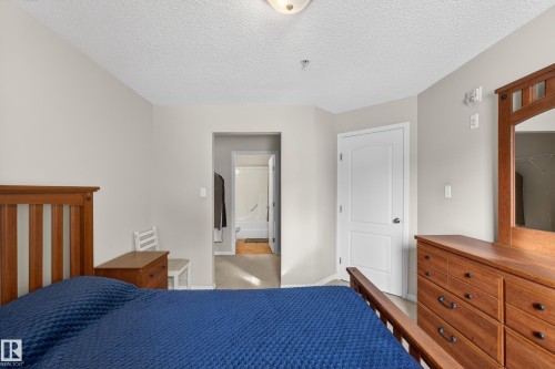 Carpeted bedroom featuring a textured ceiling and baseboards - 131 1520 Hammong Gate, Edmonton, AB - Indoor Photo Showing Bedroom