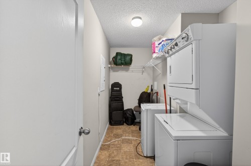 Laundry room with stacked washer / drying machine and a textured ceiling - 131 1520 Hammong Gate, Edmonton, AB - Indoor Photo Showing Laundry Room