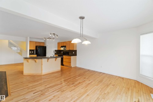 Kitchen with dark countertops, a breakfast bar, open floor plan, and light wood-type flooring - 4507 164A Avenue, Edmonton, AB - Indoor Photo Showing Kitchen