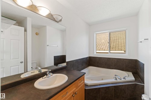 Full bathroom featuring a jetted tub, vanity, and a textured ceiling - 4507 164A Avenue, Edmonton, AB - Indoor Photo Showing Bathroom